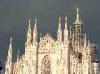 Milan (Italy): The Duomo with dark clouds behind and illuminated by the sunset sun